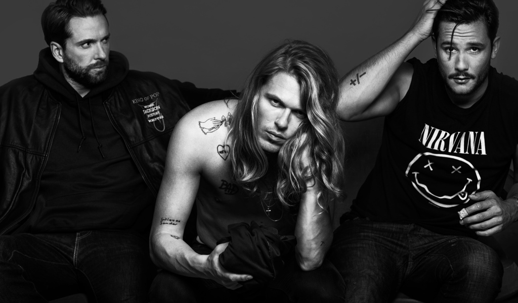 Трио Kris Kross Amsterdam в костюмах на сером фоне