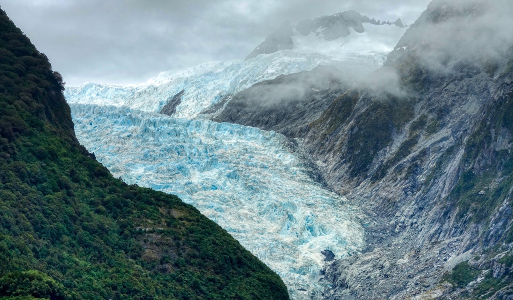 Голубой ледник между скал под грозовым небом