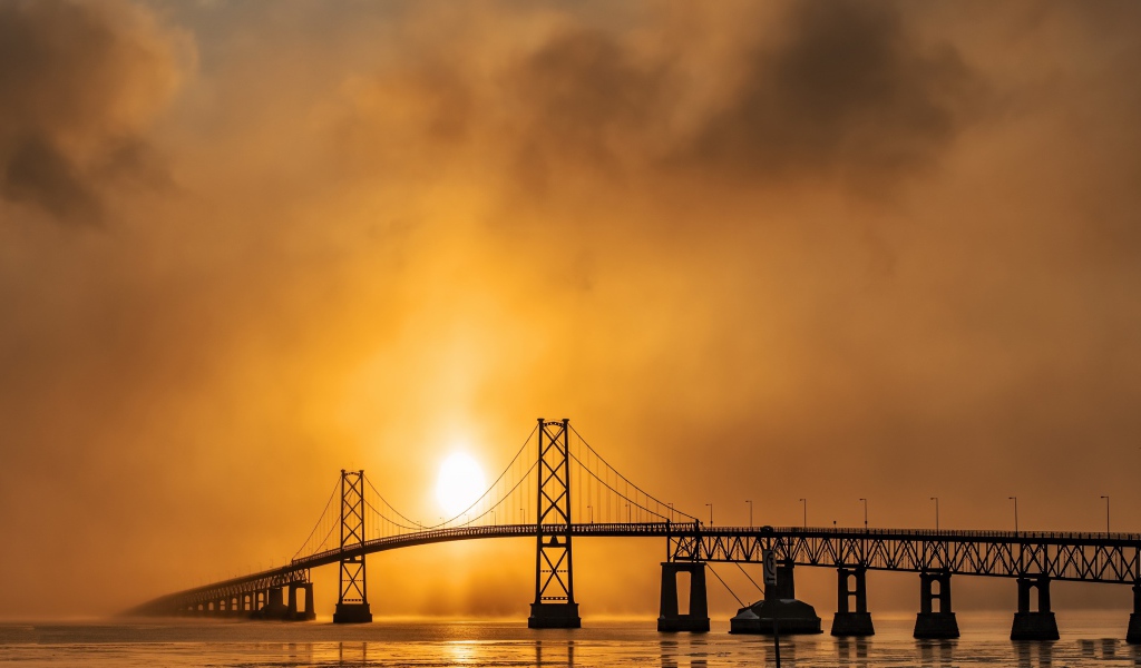 Мост через реку в тумане на восходе солнца