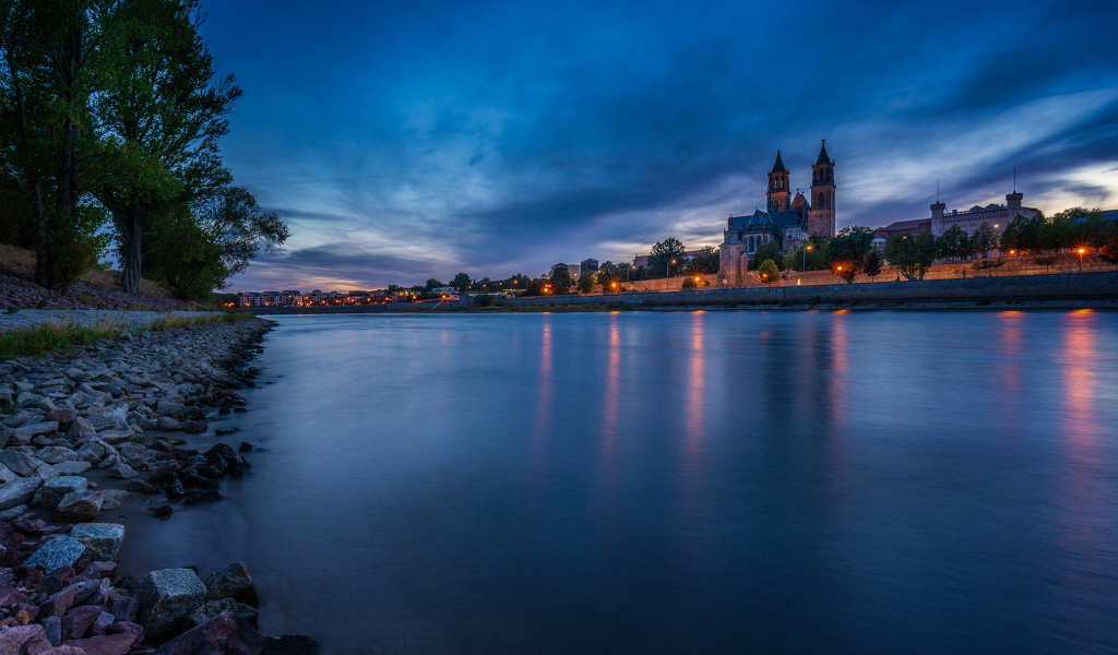 Замок у реки на фоне неба в сумерках 