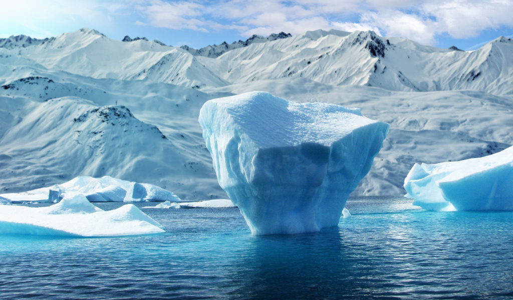 Большие глыбы льда в воде на фоне заснеженных гор 