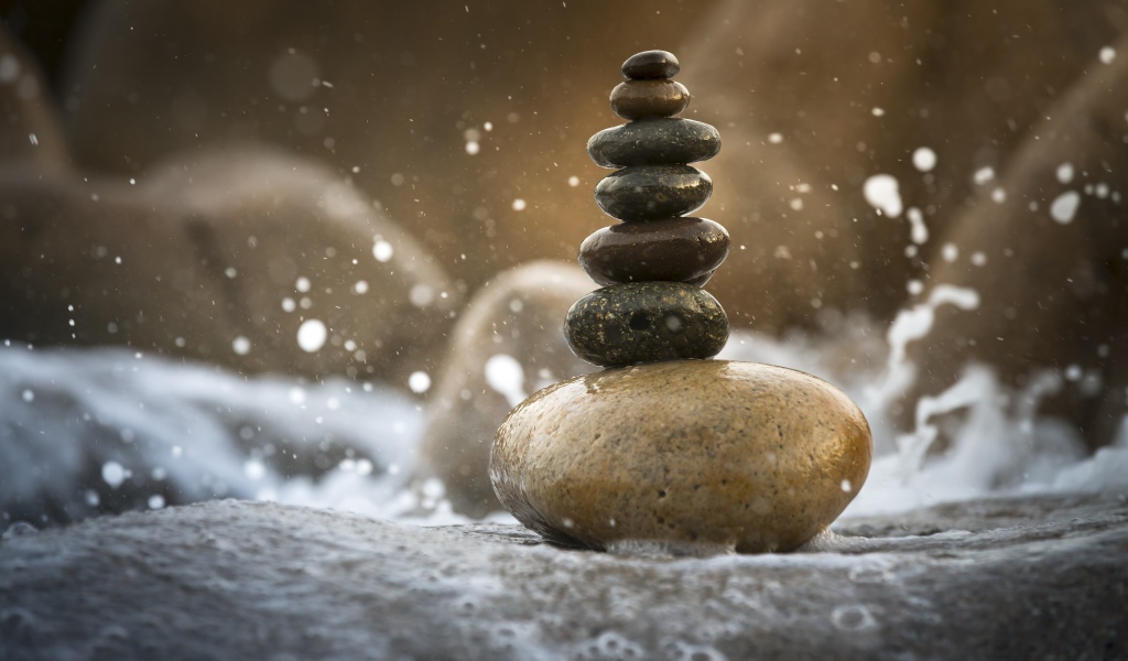 Гладкие мокрые камни в белой морской пене 