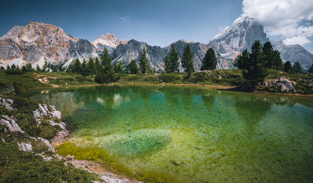 Озеро у заснеженных гор под небом с белыми облаками