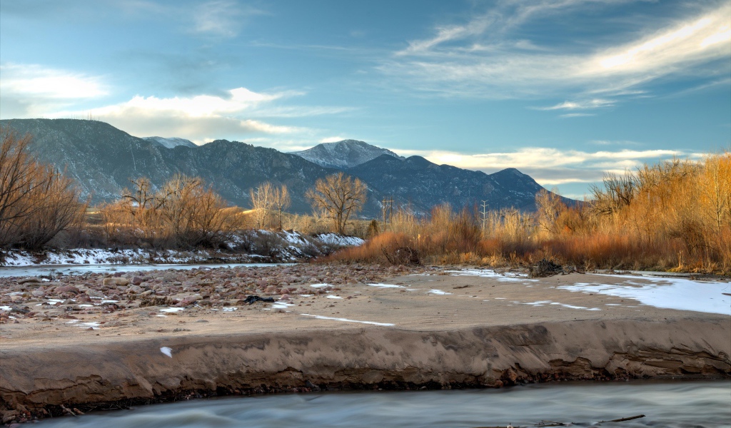 Stone river bank on a background of mountains under a blue sky
