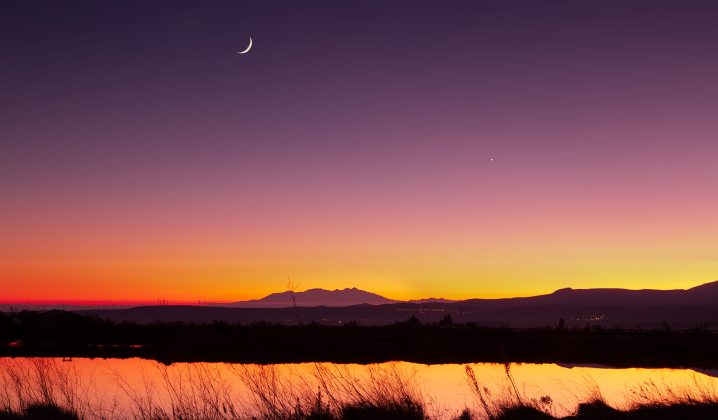 Молодой месяц в небе над озером ночью 