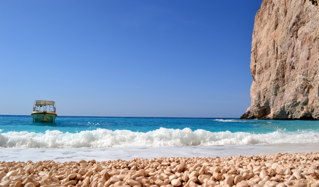 Красивая голубая вода с белыми волнами на пляже с галькой 