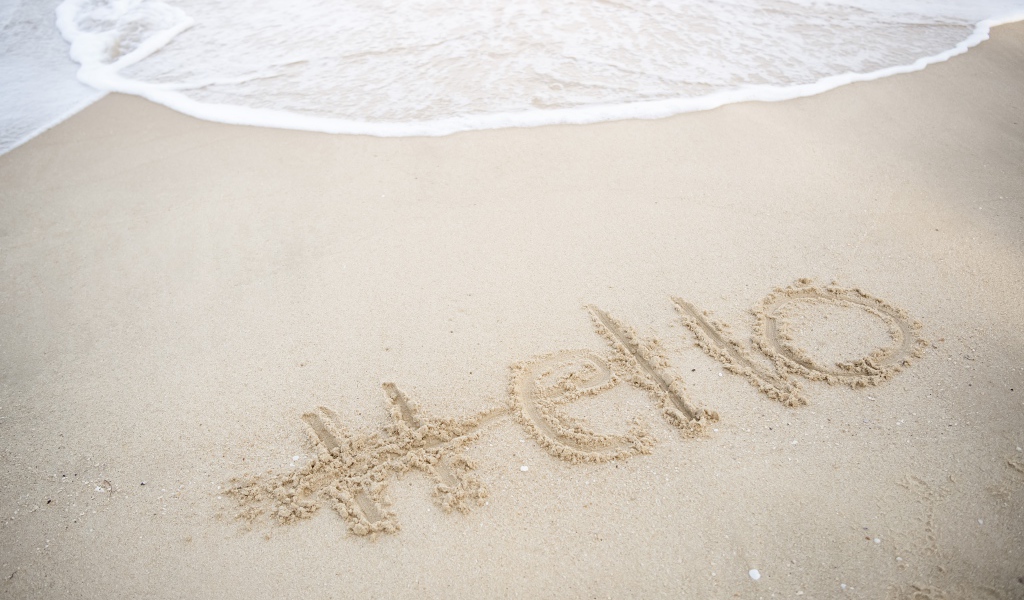 Надпись Hello на мокром песке у моря летом 
