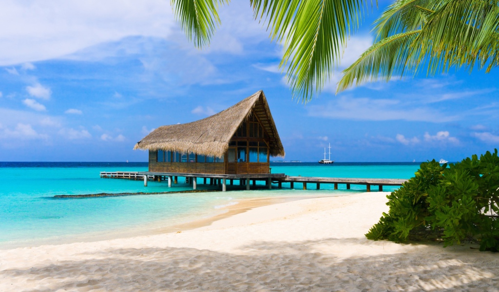 Дом на сваях на берегу тропического пляжа с белым песком