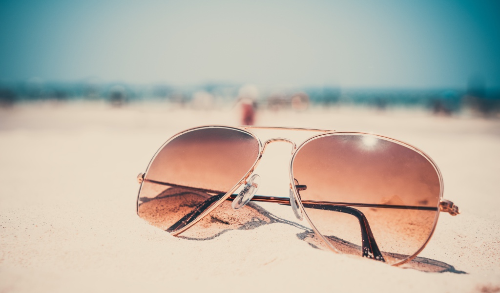 Солнечные очки лежат на горячем песке 