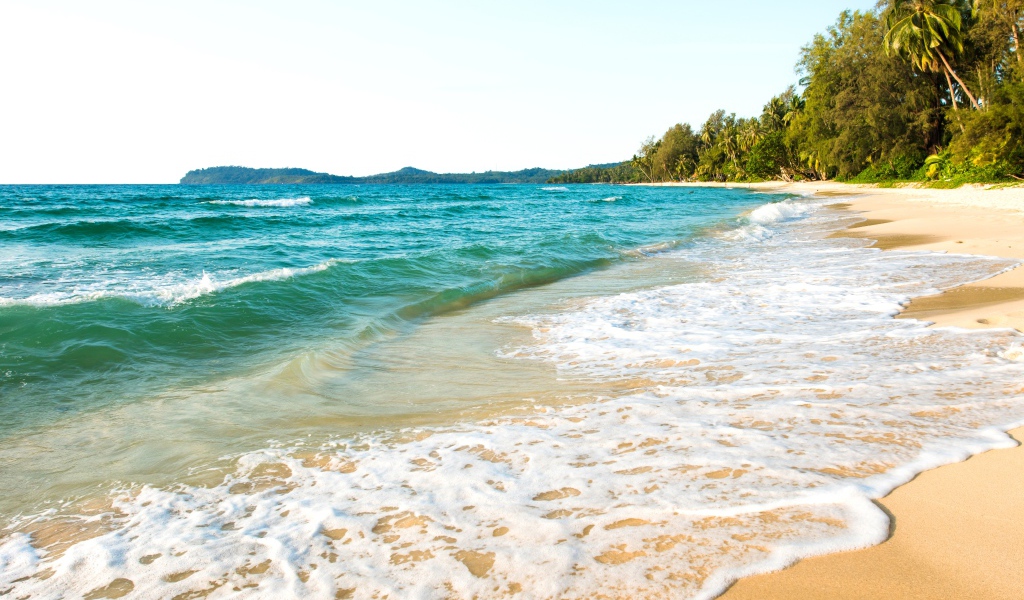 Белая пена на желтом песке тропического пляжа 