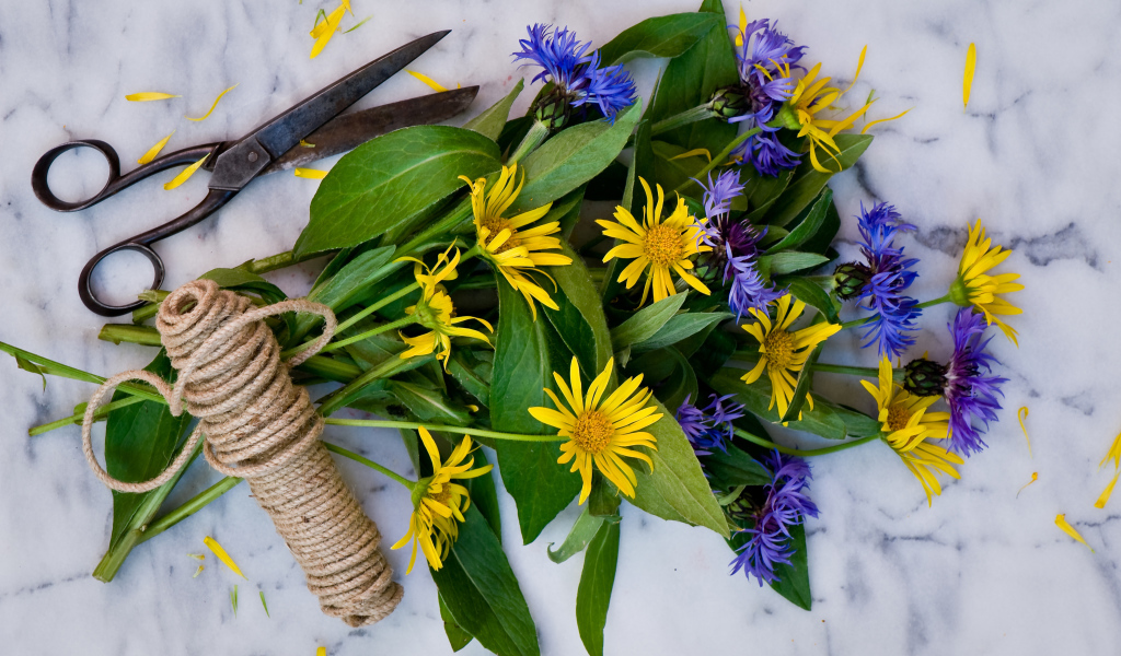 Букет васильков с желтыми цветами на столе с веревкой и ножницами