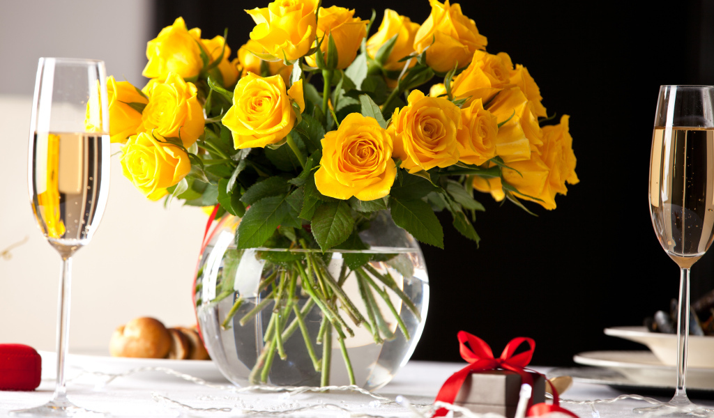 Большой букет желтых роз в вазе на столе с фужерами