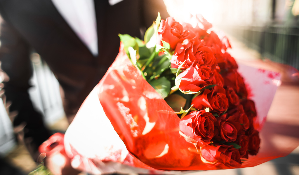 Большой красивый букет красных роз в руках мужчины 