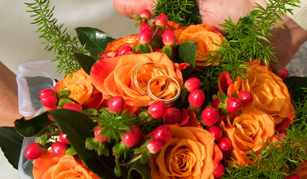 Букет оранжевых роз с красными ягодами и обручальными кольцами