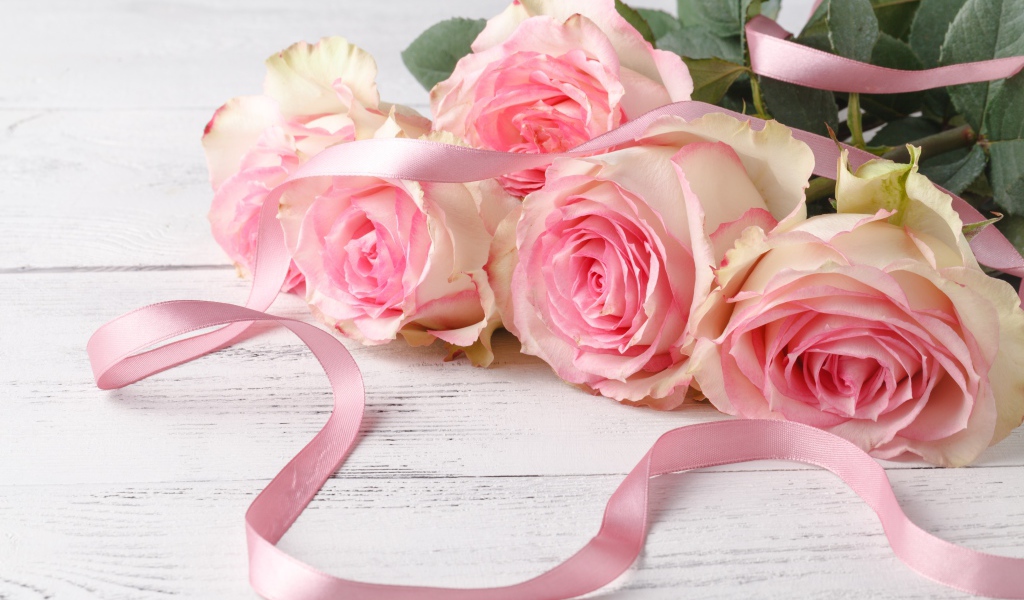 Букет розовых роз с лентой на белом столе 