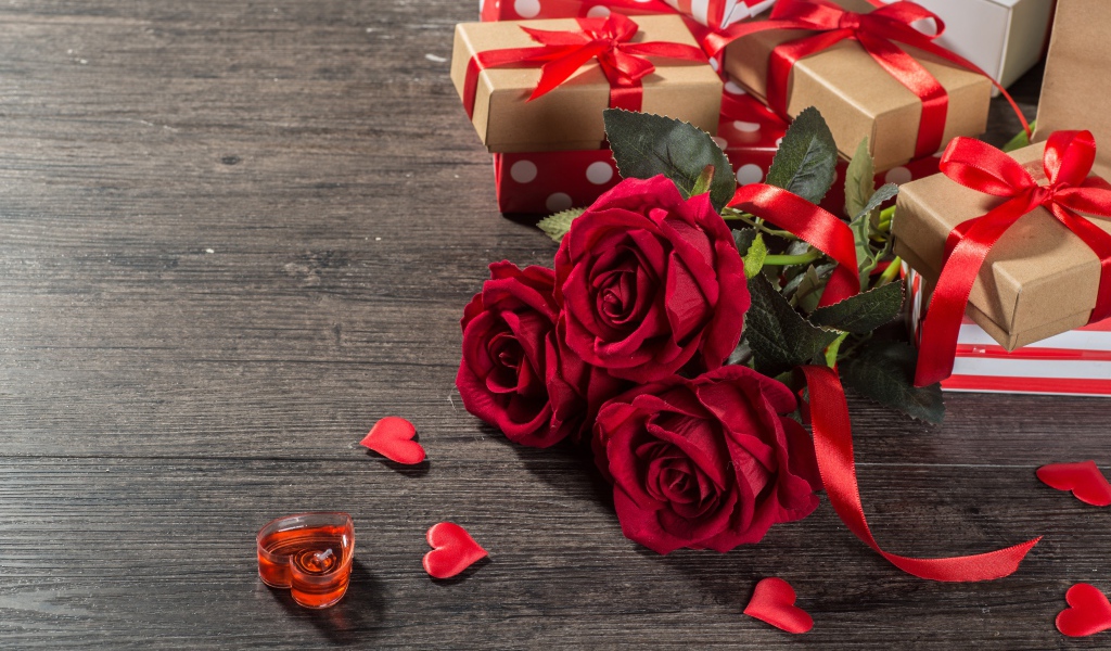 Букет красных роз и подарки на столе 