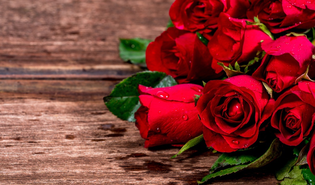 Букет красных роз на деревянном столе в каплях воды