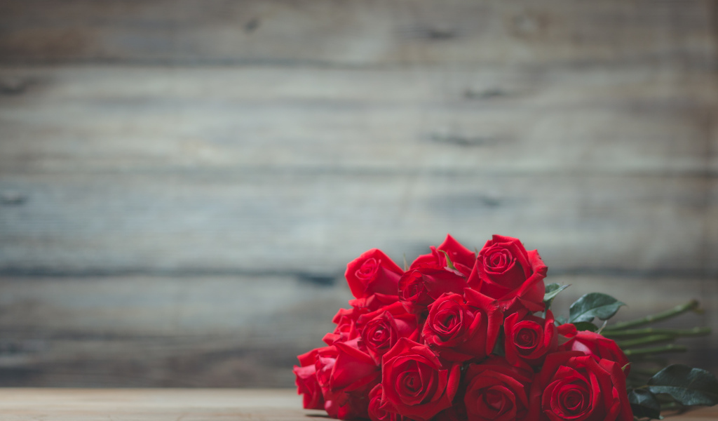 Букет красных роз на фоне деревянной стены 