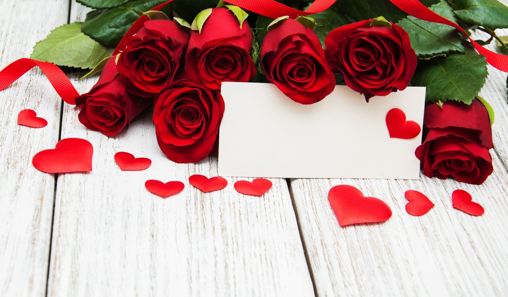 Букет красных роз на столе с сердечками и открыткой