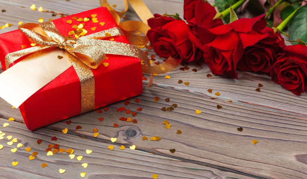 Букет красный роз с большим подарком на столе