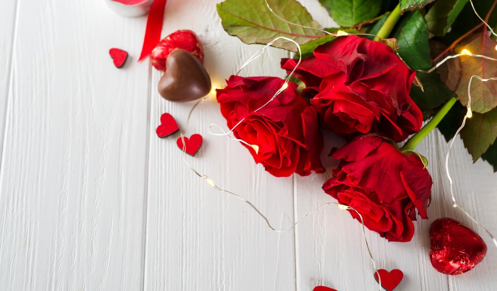 Букет красных роз с конфетами на столе