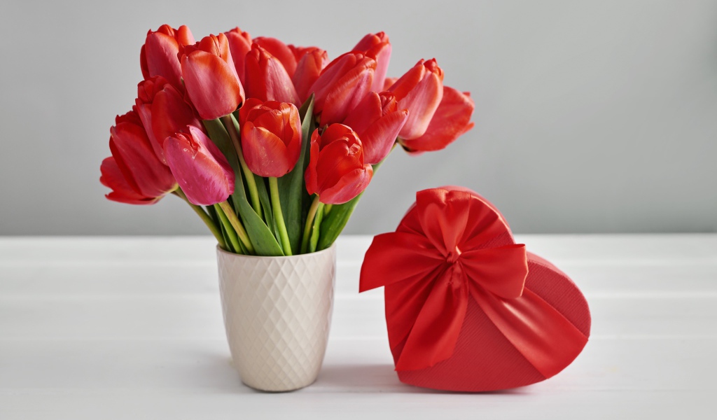 Букет красных тюльпанов на столе с коробкой в форме сердца