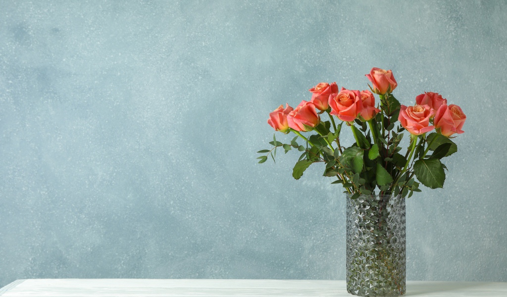 Букет роз в стеклянной вазе на сером фоне