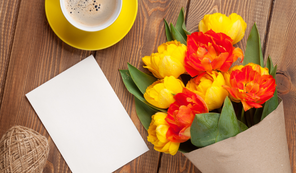 Букет тюльпанов на столе с листом бумаги и чашкой кофе