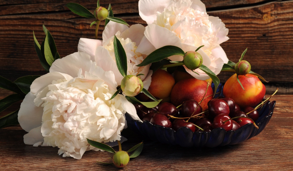Букет белых пионов на столе с нектарином и черешней