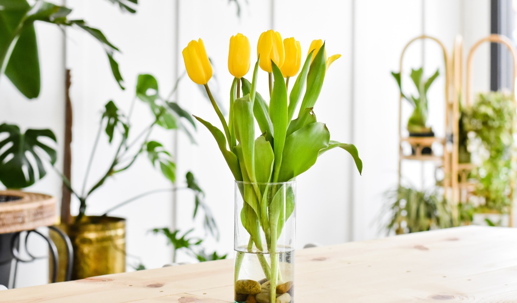 Букет желтых тюльпанов в стеклянной вазе на столе 