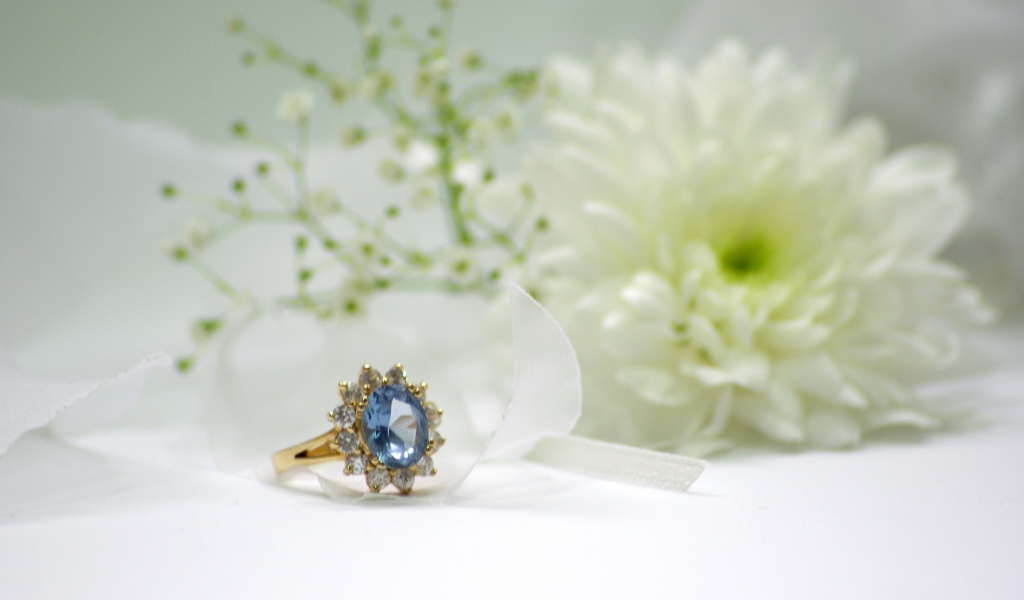 Дорогое кольцо с камнем на столе с белым цветком