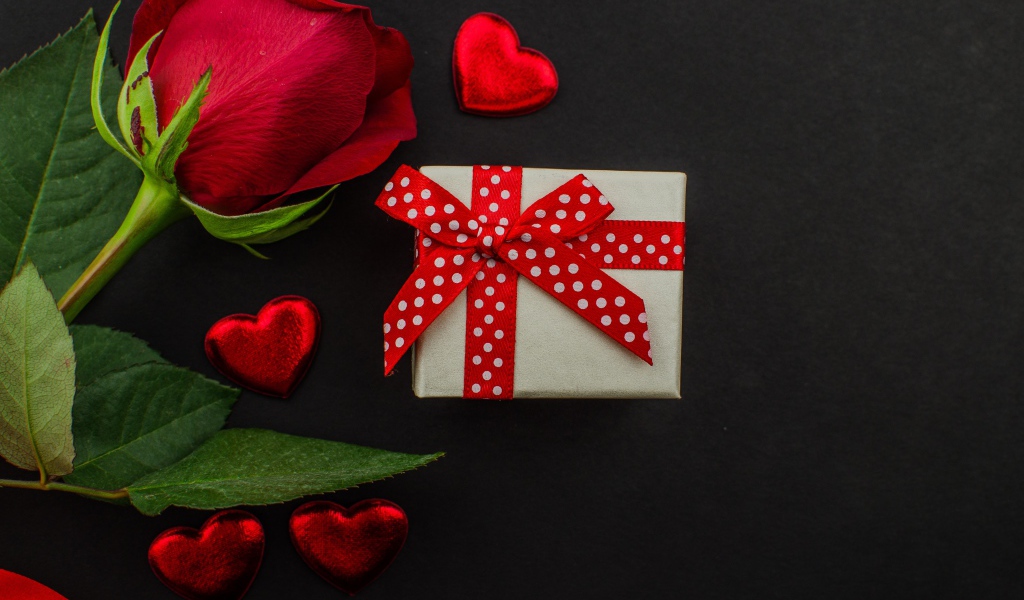 Маленький подарок и красная роза на черном столе