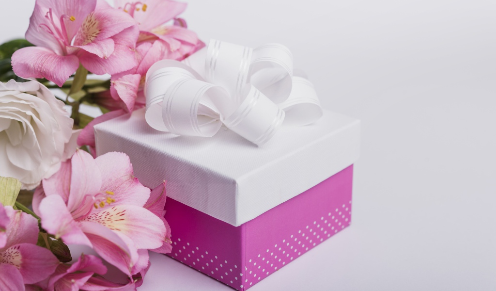 Розовые цветы альстромерии на сером фоне с подарком 