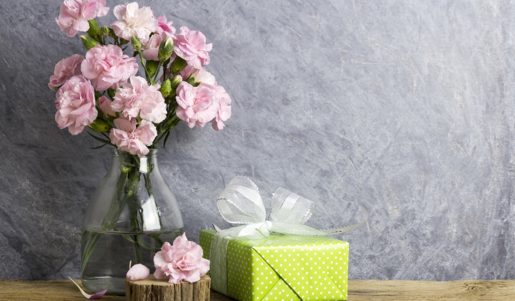 Розовые гвоздики с подарком на сером фоне