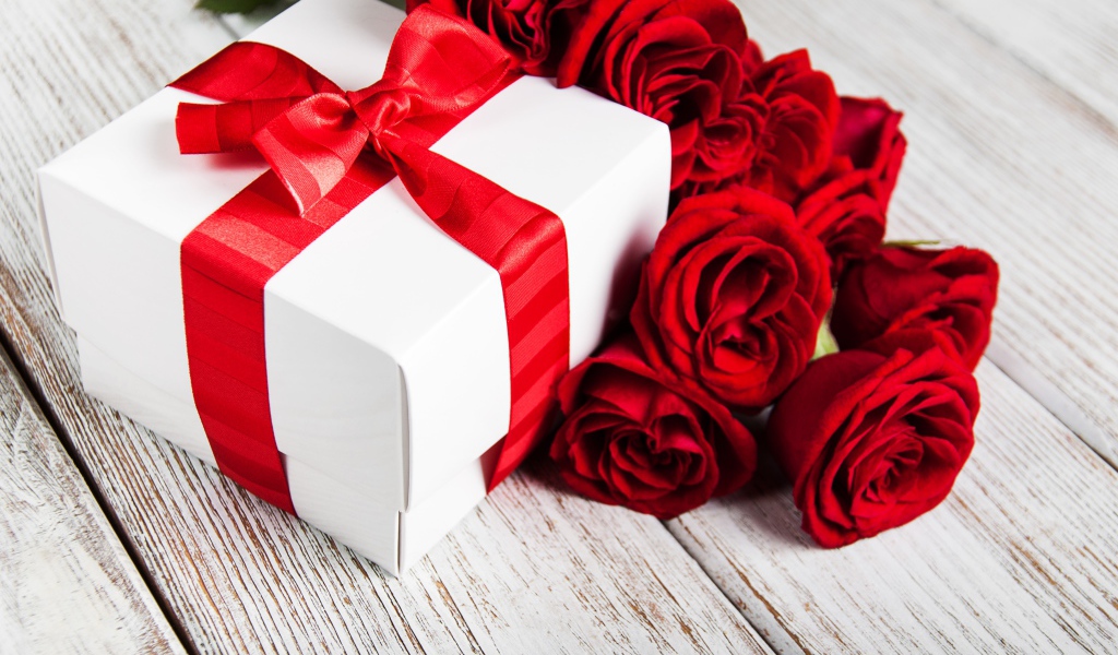 Красные розы на столе с подарком с красной лентой
