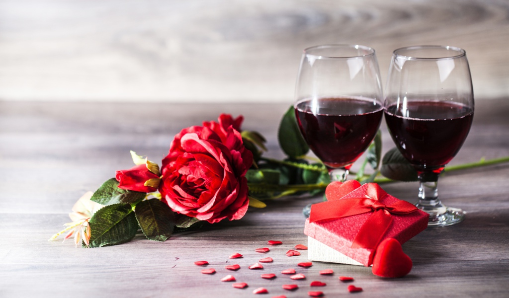 Розы, подарок и два бокала вина на столе