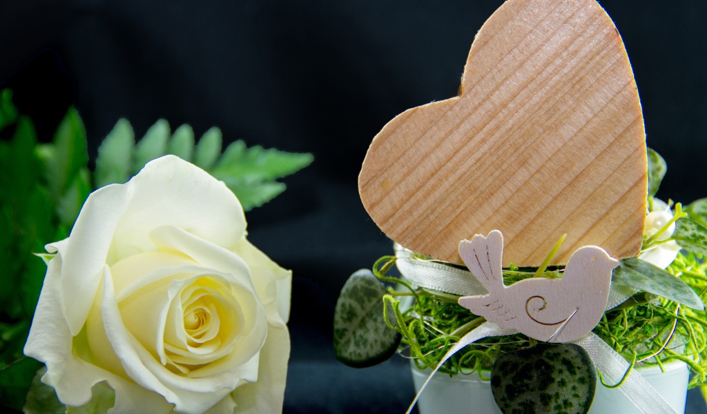 Деревянное сердце и белая роза на столе 