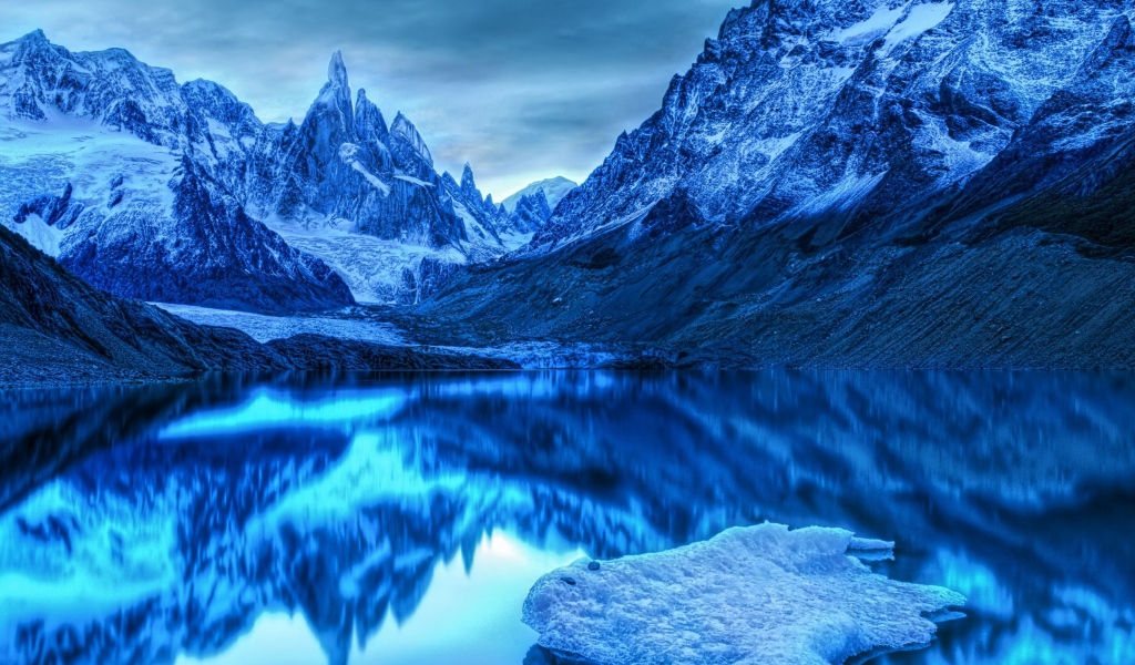 Голубой холодный закат на заснеженными горами у озера 