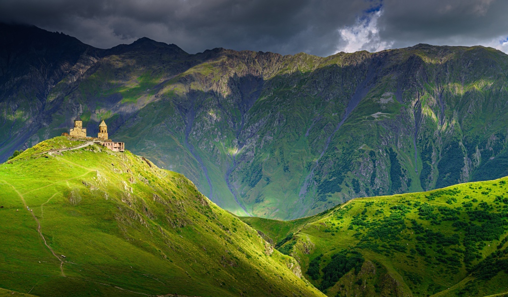 Высокие покрытые зеленой растительностью горы под грозовым небом