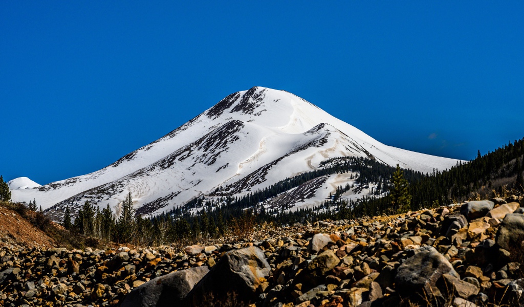Высокая заснеженная гора под голубым небом