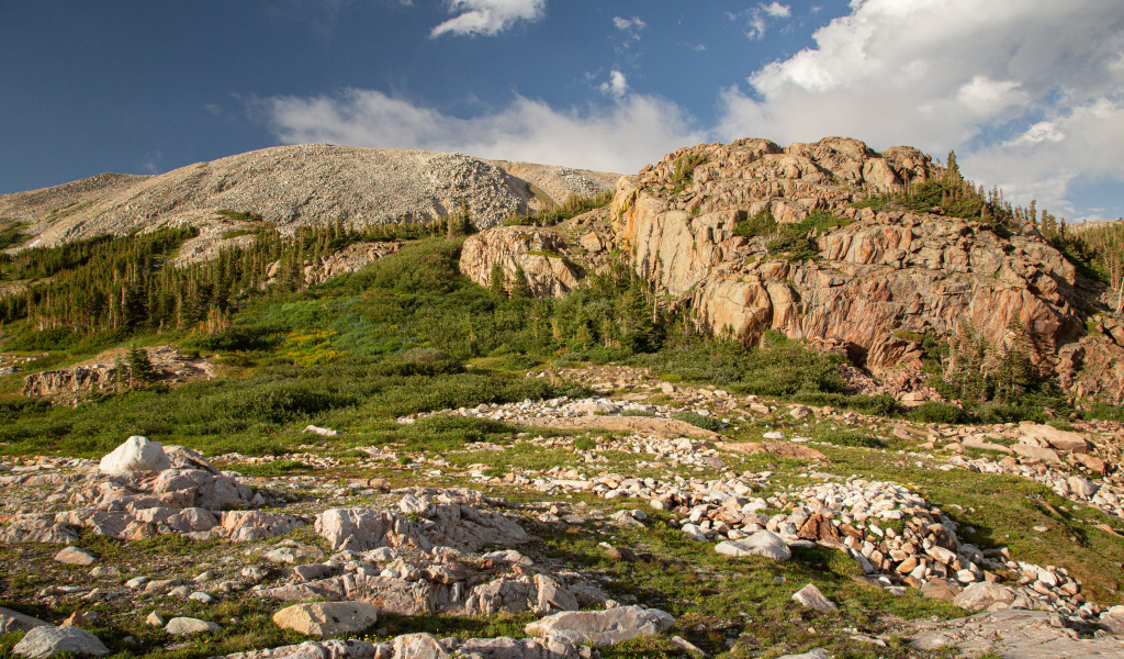 Высокие каменные горы под  голубым небом с белыми облаками