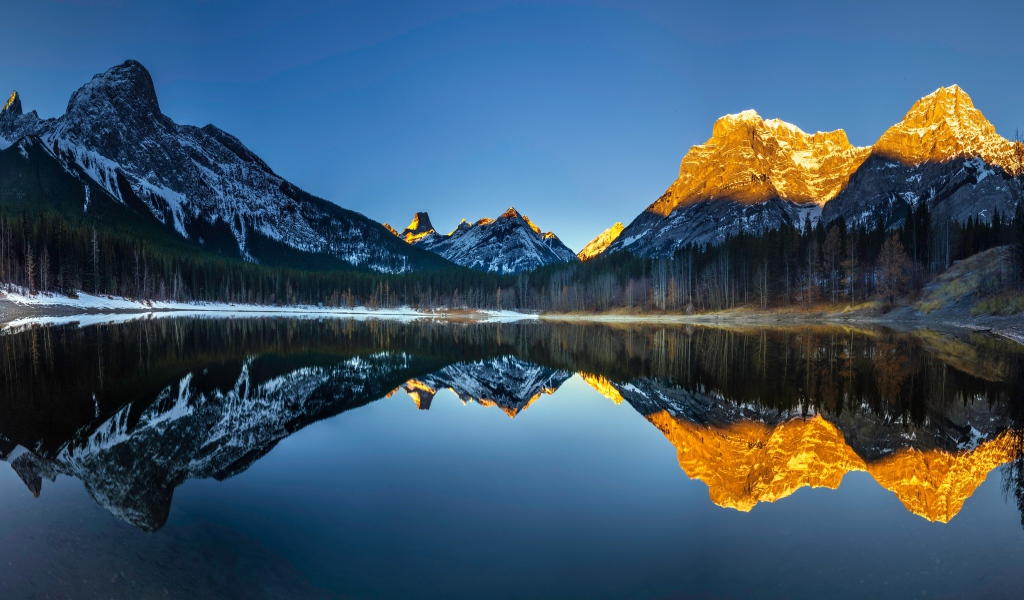 Mountain peaks in the sun are reflected in the lake