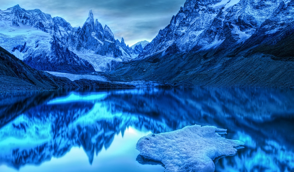 Заснеженные горы отражаются в воде в сумерках