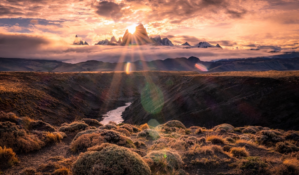 Лучи яркого солнца пробиваются сквозь вершину горы на рассвете 