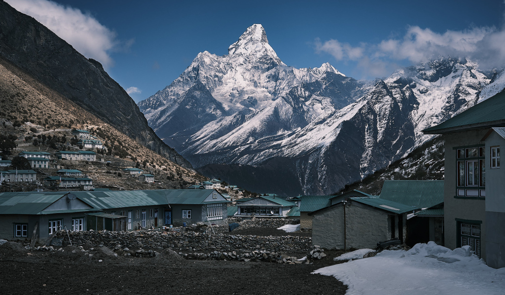 Поселок на фоне заснеженных гор под голубым небом 