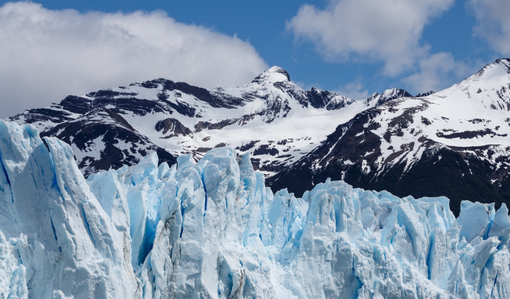Голубой ледник на фоне заснеженных гор 