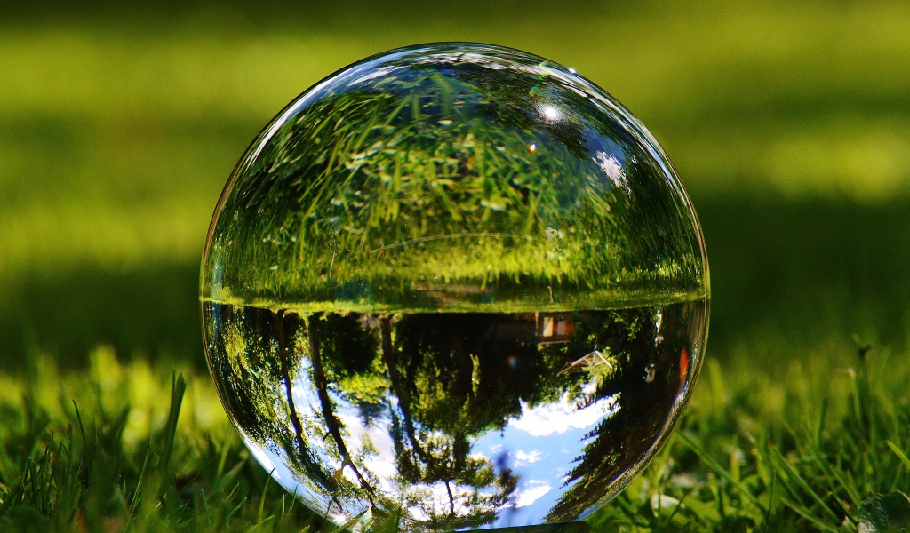 Стеклянный шар  водой на зеленой траве