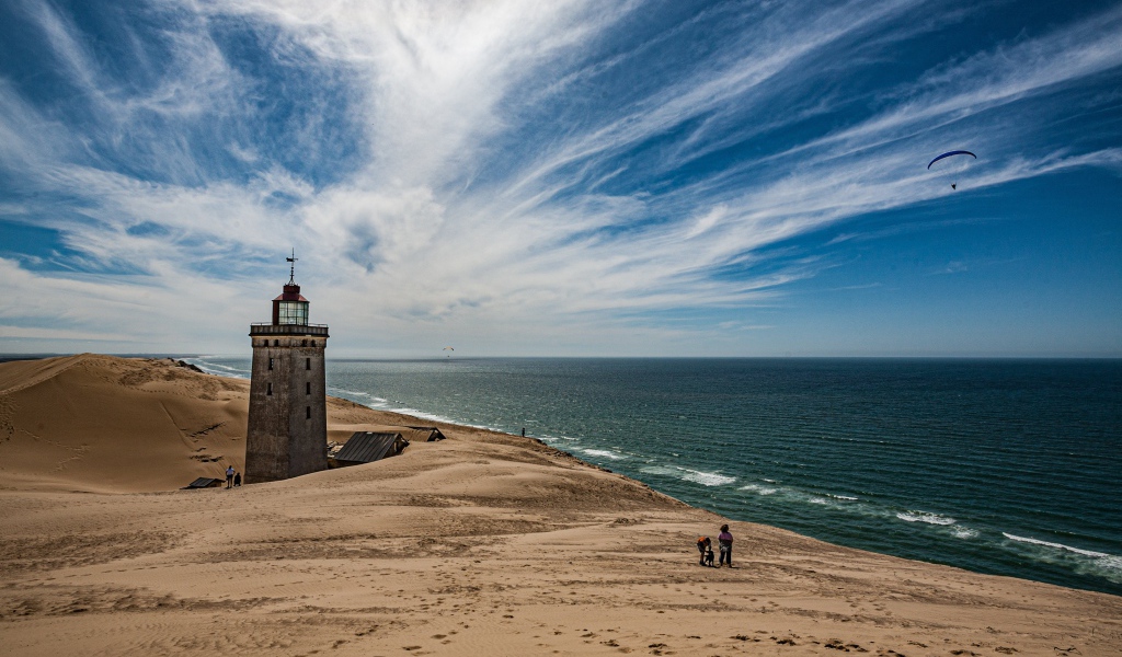 Маяк на песке на берегу моря под голубым небом