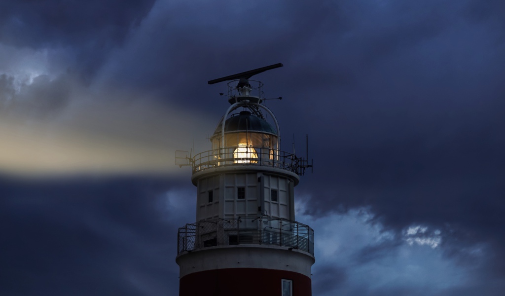 Грозовое небо над включенным маяком ночью