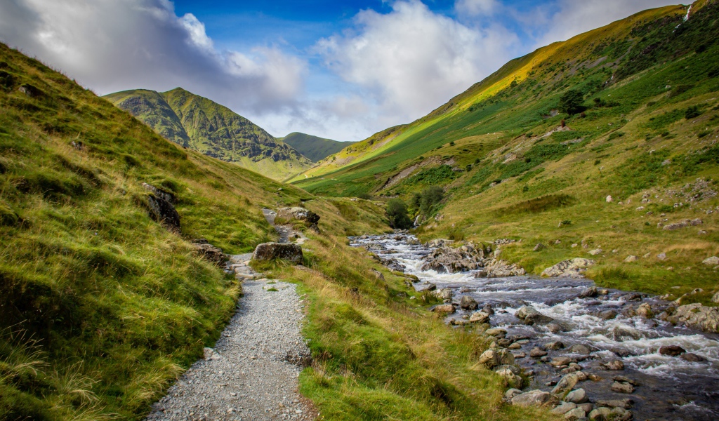 Тропа у реки на фоне покрытых зеленью гор 